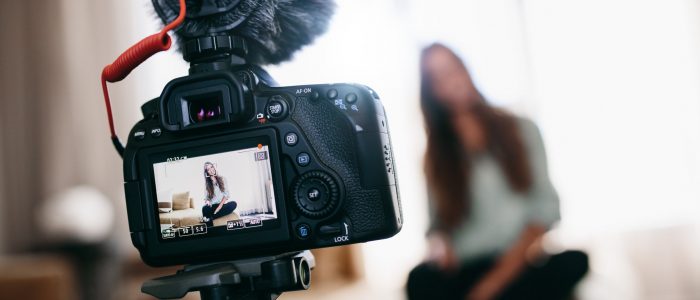 Young woman recording video for her vlog using camera with micro Woman recording content for her vlog . Camera screen showing the woman recording her vlog.